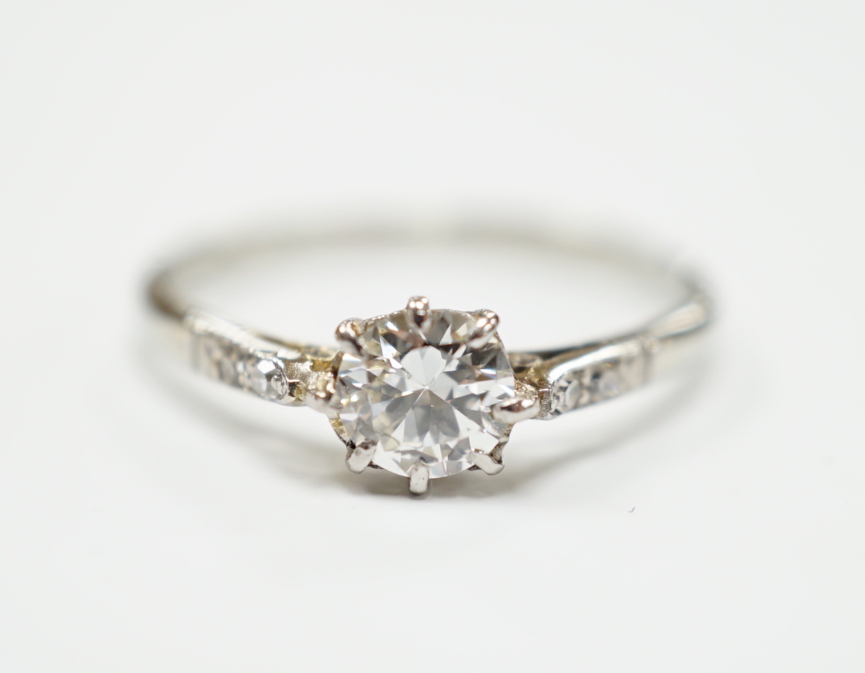 An 18ct, plat. and single stone diamond ring, with diamond set shoulders, size M/N, gross weight 1.9 grams.